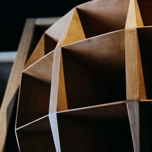 Close-up of a wooden multi-cell horn speaker cabinet, lit to show its geometric cellular construction.